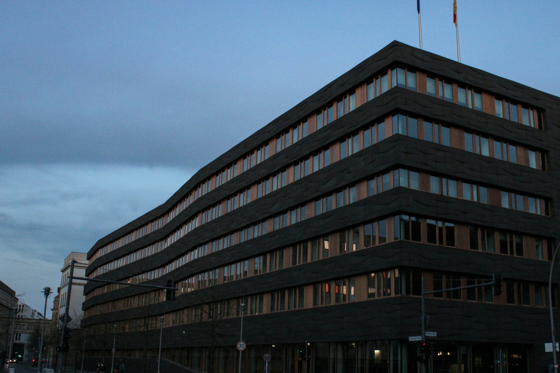 A large institutional building at dusk seen from a street corner, out of focus